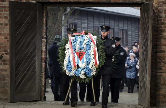 Museum security men carry a wreath at the Auschwitz Nazi death camp in Oswiecim, Poland, Monday, Jan. 27, 2020. Survivors of the Auschwitz-Birkenau death camp gathered for commemorations marking the 7 ...