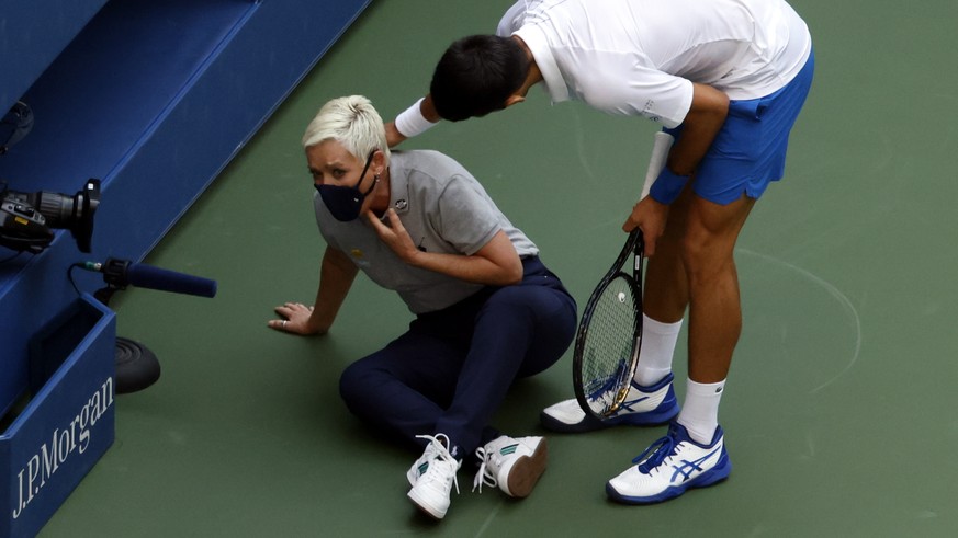 epaselect epa08651640 Novak Djokovic of Serbia (R) tries to help a linesperson after hitting her with a ball in the throat during his match against Pablo Carreno Busta of Spain on the seventh day of t ...