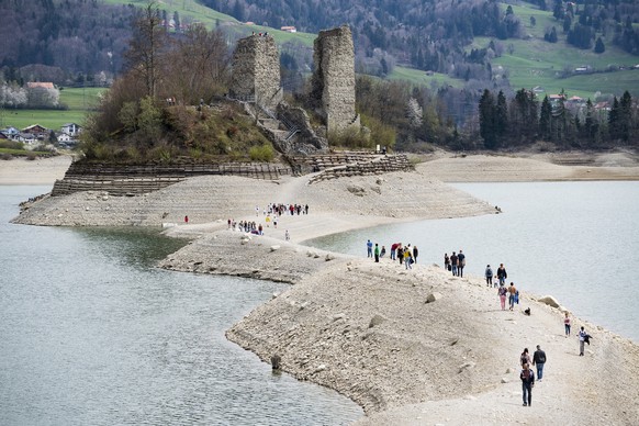 Des personnes marchent sur une bande de sable et de cailloux menant a l&#039;ile d&#039;Ogoz sur le lac de Gruyere ce dimanche 21 avril 2019 a Pont-en-Ogoz dans le canton de Fribourg. Quelques semaine ...