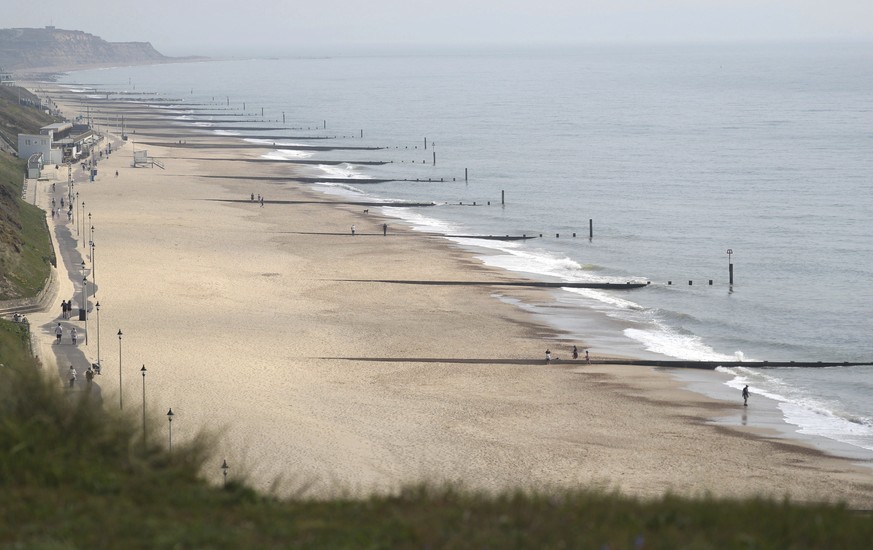 People walk along a near deserted Southbourne beach as the UK continues in lockdown to help curb the spread of the coronavirus, in Southbourne, south England, Friday April 10, 2020. The highly contagi ...