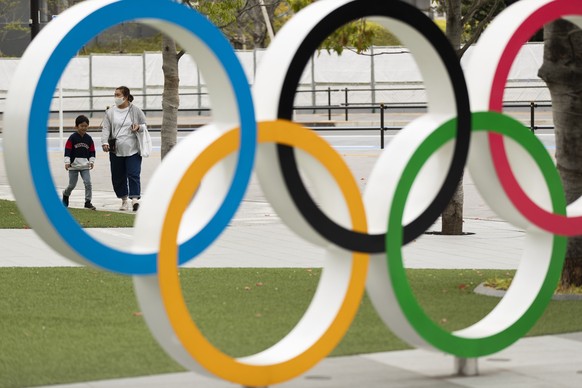 A mother and a boy walk by a display of the Olympic rings at the Japan Olympic Museum in Tokyo on Friday, April 2, 2021. Reports in Japan on Tuesday, April 6, 2021, said Tokyo Olympic organizers have  ...