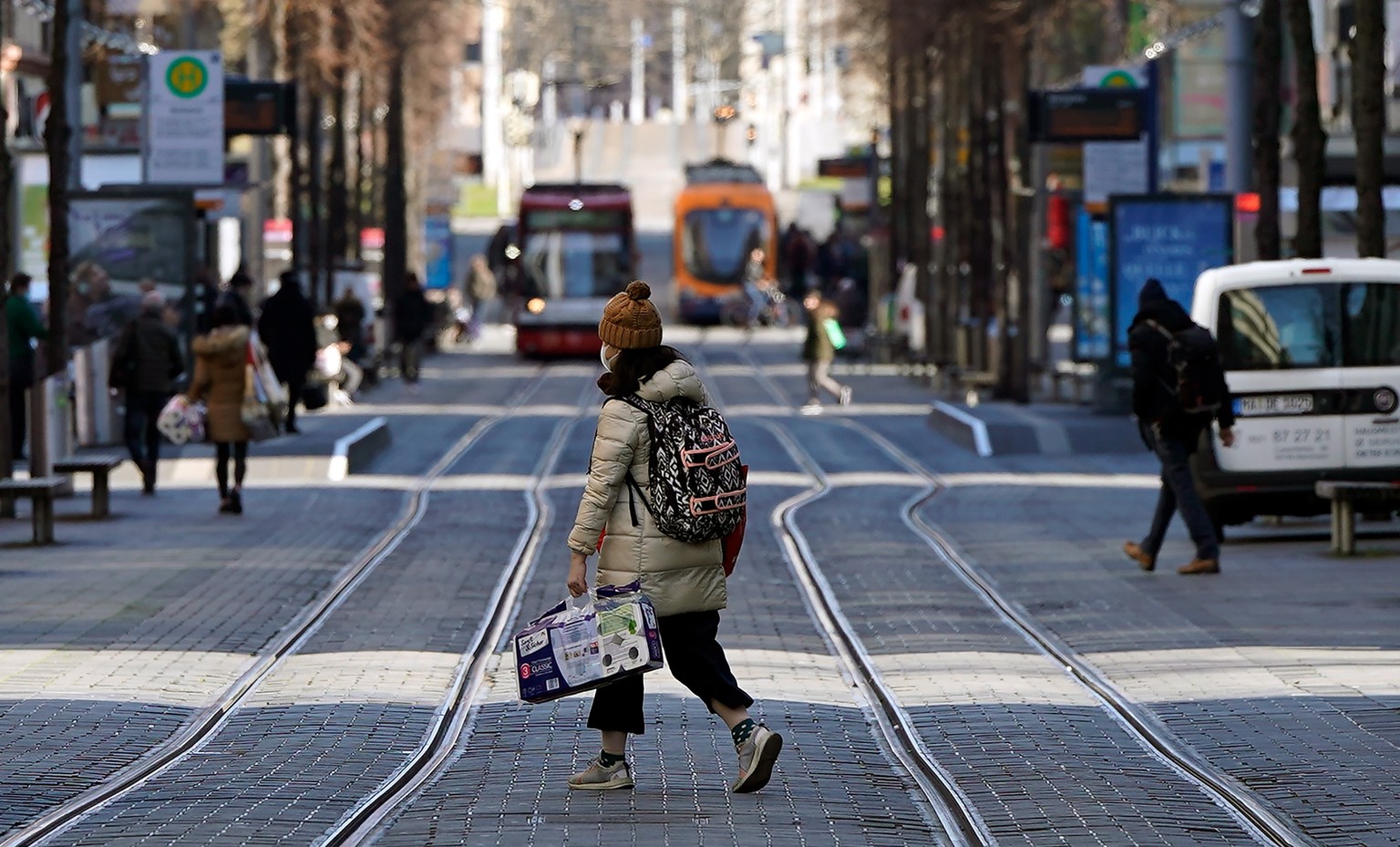 epa08314950 A woman with toilet paper walks across an otherwise empty street at the so-called &#039;Planken&#039; quarter in Mannheim, Germany, 23 March 2020. Germany inplemented more severe restricti ...
