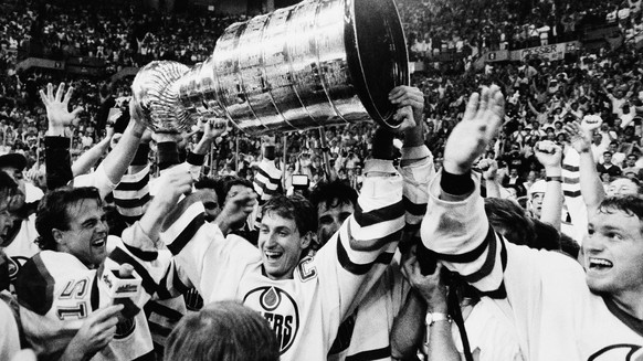 Edmonton Oilers team caption Wayne Gretzky is flanked by teammates as he skates with the Stanley Cup following their 3-1 victory over the Philadelphia Flyers in the seventh game of the Stanley Cup fin ...