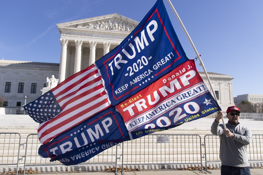 epa08878008 A supporter of US President Donald J. Trump holds a flag outside the Supreme Court in Washington, DC, USA, 11 December 2020. Eighteen US state attorneys general have sided with Texas in at ...