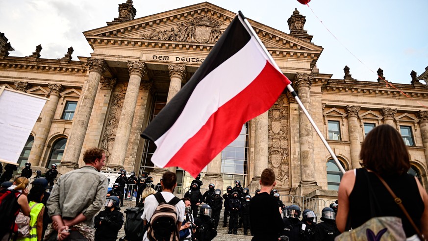 29.08.2020, Berlin: Teilnehmer einer Kundgebung gegen die Corona-Massnahmen stehen vor dem Reichstag, ein Teilnehmer haelt eine Reichsflagge. (KEYSTONE/DPA/Fabian Sommer)