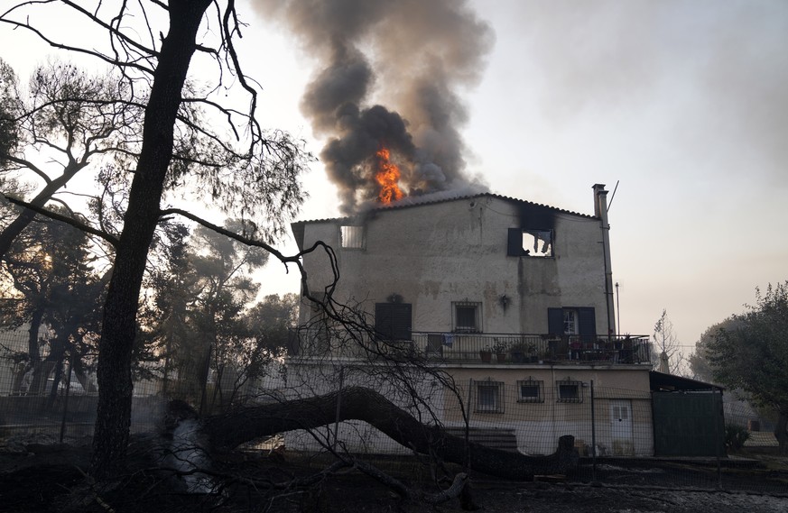 A house is on fire in Varibobi area, northern Athens, Greece, Wednesday, Aug. 4, 2021. More than 500 firefighters struggled through the night to contain a large forest blaze on the outskirts of Athens ...