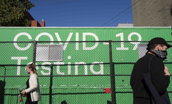 epa08724499 People walk past a sign for a COVID testing site in the Williamsburg neighborhood of Brooklyn, New York, USA, on 06 October 2020. There has been a recent rise in the percentage of positive ...