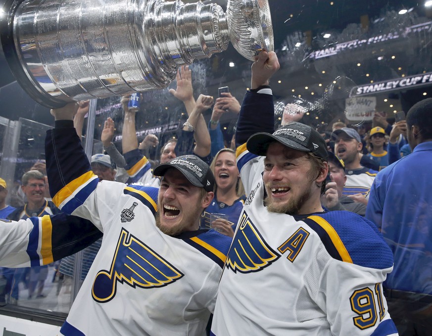 St. Louis Blues&#039; Ivan Barbashev, left, and Vladimir Tarasenko, both of Russia, hold the Stanley Cup as fans in the stands celebrate after the Blues defeated the Boston Bruins in Game 7 of the NHL ...