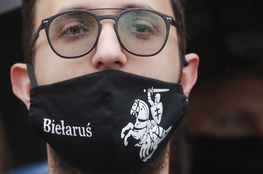 Belarusian opposition supporter wearing a face mask with an old Belarusian national emblem attends a protest rally in front of the government building at Independent Square in Minsk, Belarus, Wednesda ...