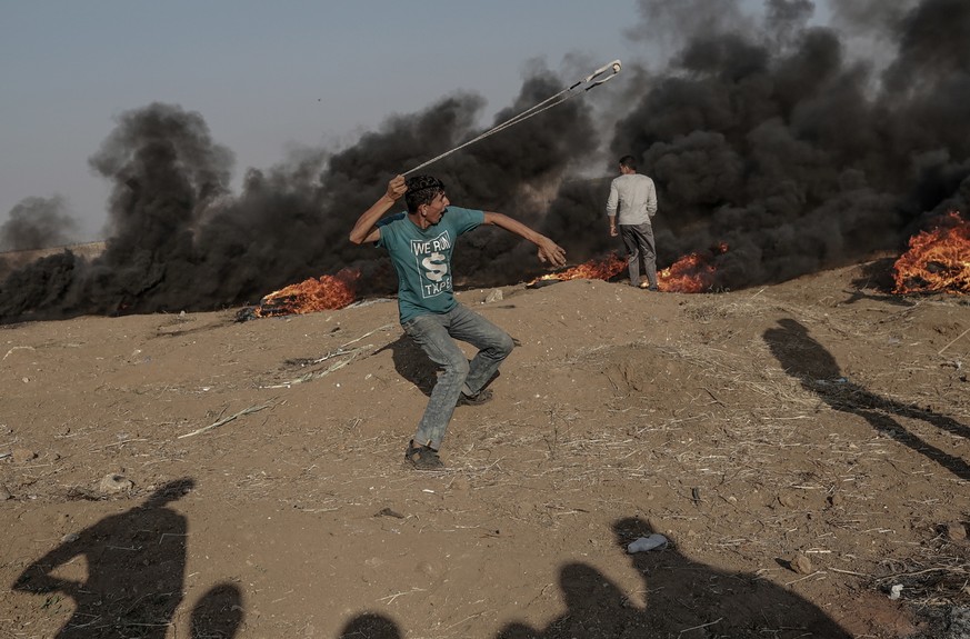 epa06740335 A Palestinian protester throw stones during clashes near the border with Israel in the east of Gaza Strip, 15 May 2018. At least 62 Palestinian protesters were killed and more than 2,500 o ...