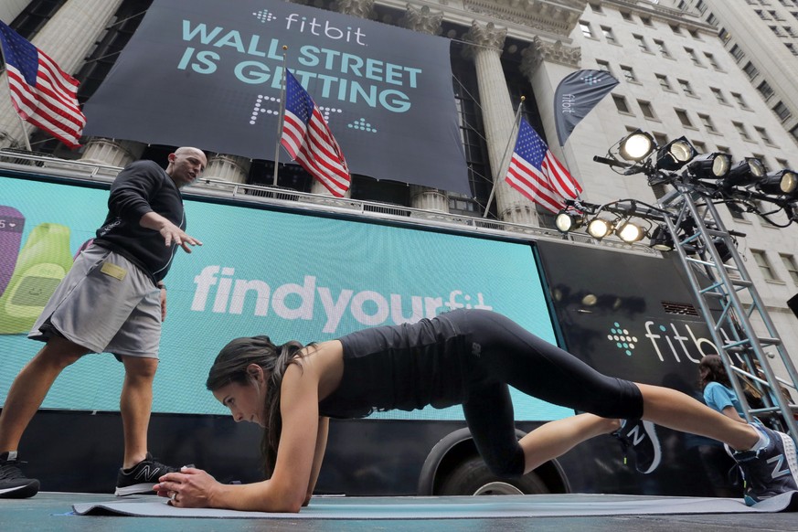 Fitness expert Harley Pasternak, left, and actress Jordana Brewster lead a work out on behalf of Fitbit, in front of the New York Stock Exchange, Thursday, June 18, 2015. Fitbit flexed some muscle Thu ...