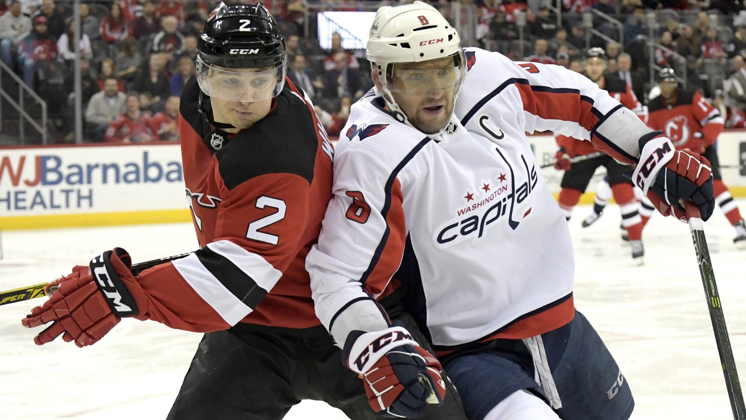 Washington Capitals left wing Alex Ovechkin (8) and New Jersey Devils defenseman Colton White (2) chase after the puck during the first period of an NHL hockey game Saturday, Feb. 22, 2020, in Newark, ...
