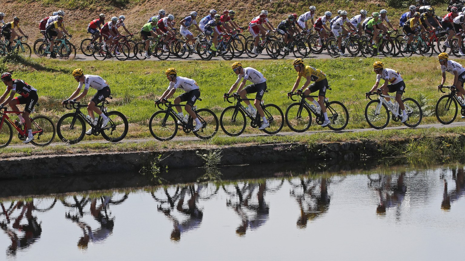 FILE - In this July 5, 2017 file photo, the pack with Britain&#039;s Geraint Thomas, wearing the overall leader&#039;s yellow jersey, is reflected in a pond during the fifth stage of the Tour de Franc ...