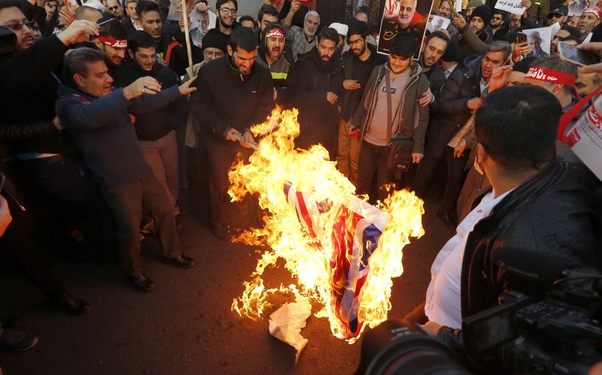 epa08122611 Iranian hardliners burn British and Israeli flags during a protest in front of the British embassy, in Tehran, Iran, 12 January 2020. According to reports, hundreds of Iranian hardliners g ...