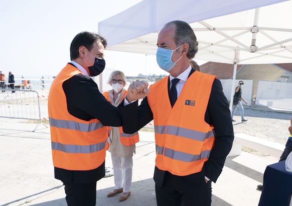 epa08538535 A handout photo made available by Chigi Palace Press Office shows Italian Premier Giuseppe Conte with Veneto Region Governor Luca Zaia attending the general test of the Mose Sluice Gates,  ...