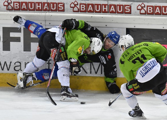Der Davoser Beat Forster, Mitte, wird von Fribourgs Benjamin Neukom, links, und Killian Mottet an die Bande gestossen, waehrend dem Eishockey-Qualifikationsspiel der National League A zwischen dem HC  ...