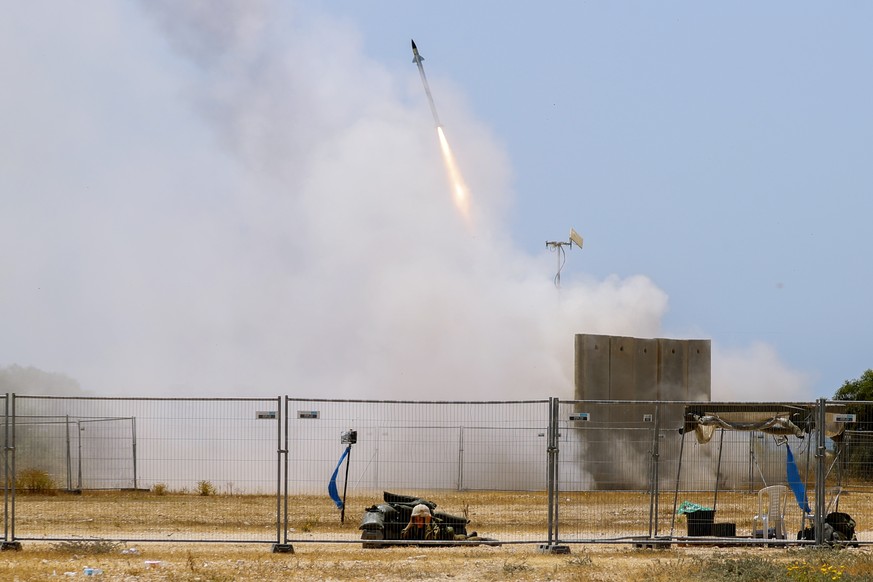 A Israeli soldier takes cover as an Iron Dome air defense system launches to intercept a rocket from the Gaza Strip, in Ashkelon, southern Israel, Tuesday, May 11, 2021. (AP Photo/Ariel Schalit)