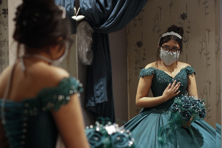 Ximena Canejo Hernandez checks her reflection in a mirror as she tries on her chosen Quinceanera dress, in central Mexico City, Friday, July 10, 2020. Ximena&#039;s family, wanting to give her a tradi ...