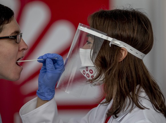 For demonstration purposes, an employee of the Centogene company takes a throat swab from a colleague at the airport in Frankfurt, Germany, Monday, June 29, 2020. In the future, people will be able to ...