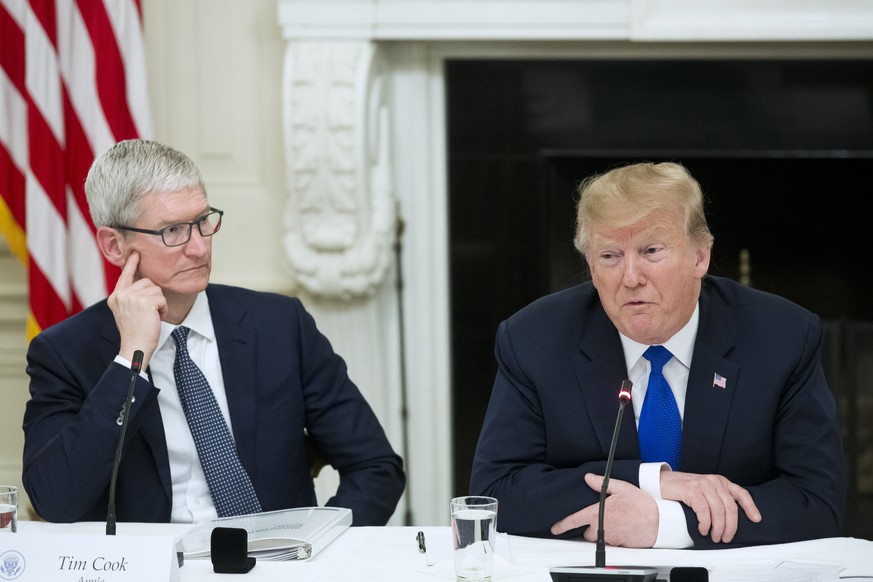 epa07418295 Chief Executive Officer of Apple Inc. Tim Cook (L) listens to US President Donald J. Trump (R) deliver remarks while participating in an American Workforce Policy Advisory Board meeting in ...