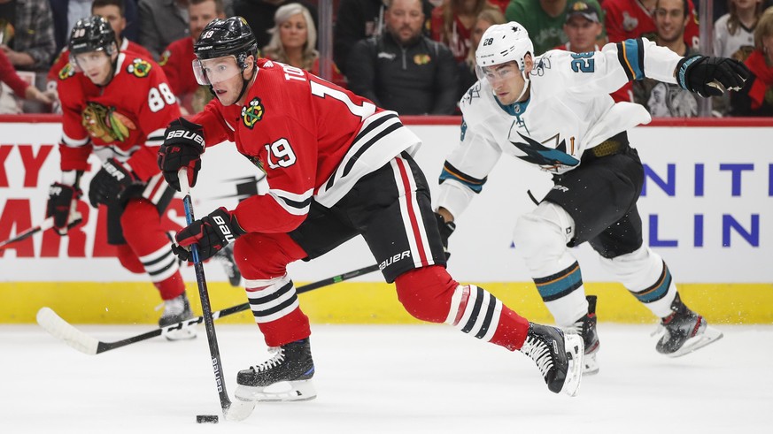 Chicago Blackhawks center Jonathan Toews (19) looks to pass the puck away from San Jose Sharks right wing Timo Meier (28) during the first period of an NHL hockey game Thursday, Oct. 10, 2019, in Chic ...