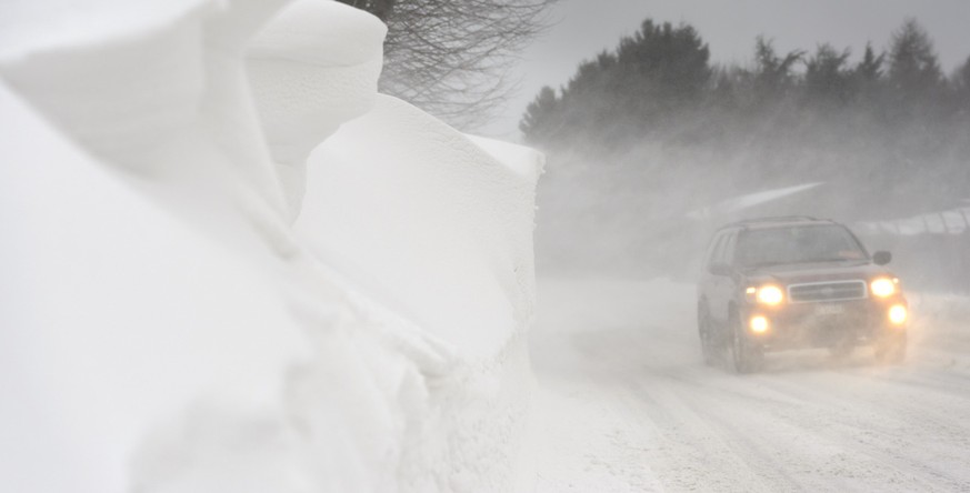 Une voiture roule sur la route couverte de neige suite a une tempete de vent, bise, qui a egalement forme des congeres ce jeudi 5 fevrier 2015 a Denens, Vaud. Les regions du Pied du Jura et du Jorat s ...