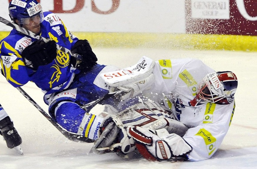 Davos player Peter Guggisberg, left, vies for the puck with Mannheim&#039;s goalkeeper Fred Brathwaite, right, during the game between Swiss Team HC Davos and German team Adler Mannheim at the 83rd Sp ...