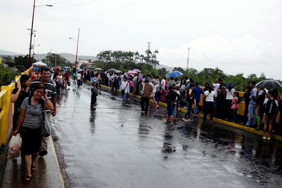 People line up (R) to cross over the Simon Bolivar international bridge to Colombia to take advantage of the temporary border opening as others come back after shopping in San Antonio del Tachira, Ven ...