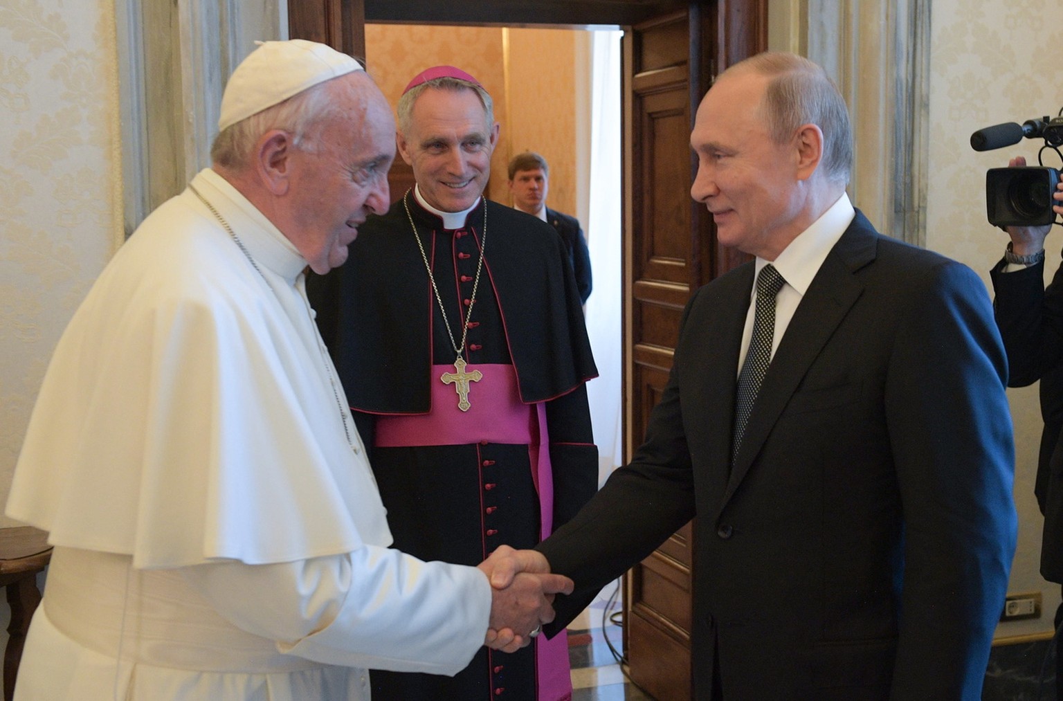 epa07695023 Pope Francis (L) and Russian President Vladimir Putin (R) shake hands as Archbishop Georg Ganswein (2-L) looks on during their meeting at the Vatican, 04 July 2019. Putin arrived for a one ...