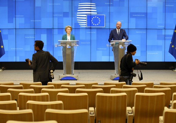 Photographers move around in a nearly empty press room as European Council President Charles Michel, right, and European Commission President Ursula von der Leyen, left, speak after a video-conference ...