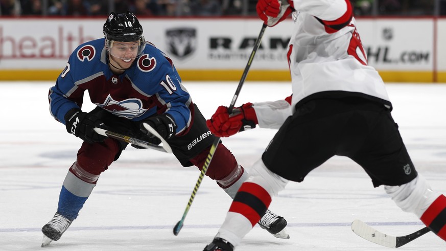 Colorado Avalanche right wing Sven Andrighetto, left, reaches for the puck as New Jersey Devils defenseman Colton White covers in the third period of an NHL hockey game Sunday, March 17, 2019, in Denv ...