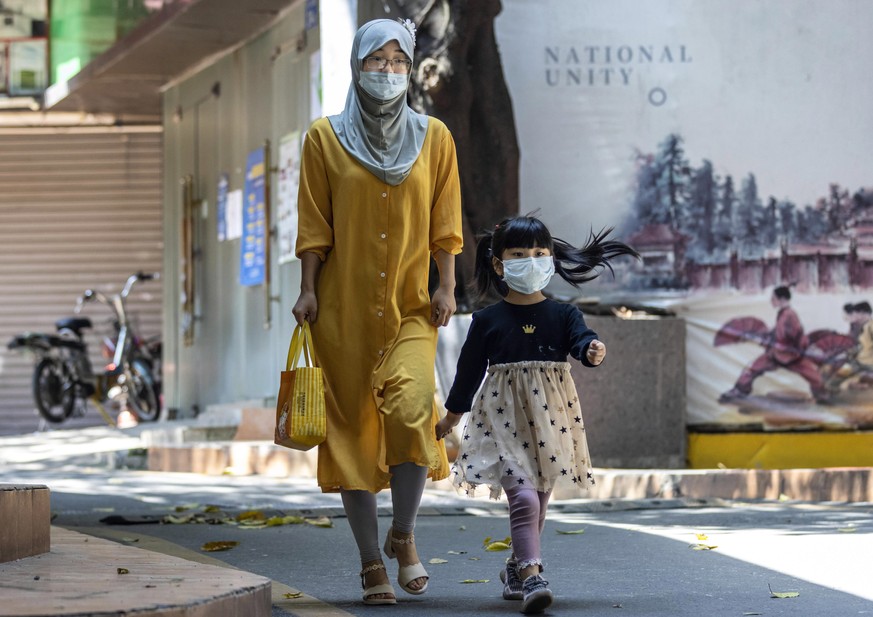 epa08391577 A woman and child wearing masks walk in the African Village part of Guangzhou, Guangdong province, China, 29 April 2020. African Village also known as Little Africa in Guangzhou, where mos ...