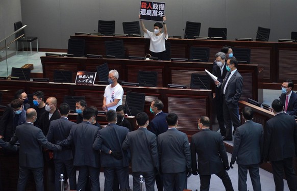 Pro-democracy lawmaker Tanya Chan, center, holds a placard reading &quot;A murderous regime stinks for ten thousand years&quot; as they protest at the main chamber of the Legislative Council in Hong K ...