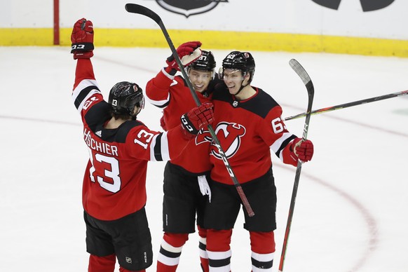 New Jersey Devils center Nico Hischier (13), and left wing Nikita Gusev (97) celebrate with Devils left wing Jesper Bratt (63) after Bratt scored a game-tying goal in the third period of an NHL hockey ...