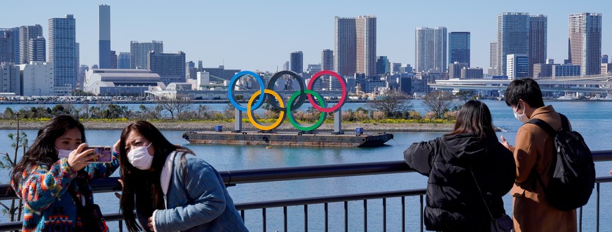 epa08273711 Visitors wearing masks take photos near the Olympic rings in Tokyo, Japan, 06 March 2020. According to Japan&#039;s Olympic Minister, the Coronavirus outbreak has forced several major even ...