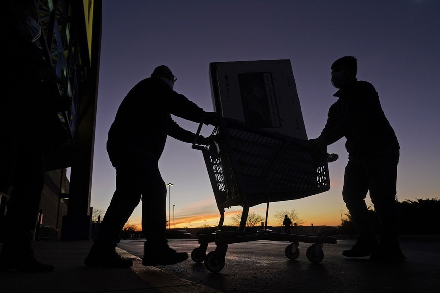 People transport a television to their car after shopping during a Black Friday sale at a Best Buy store Friday, Nov. 26, 2021, in Overland Park, Kan. Retailers are expected to usher in the unofficial ...