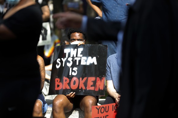 A protester listens during a rally in Detroit, Thursday, June 4, 2020, over the death of George Floyd, who died May 25 after being restrained by police in Minneapolis. (AP Photo/Paul Sancya)