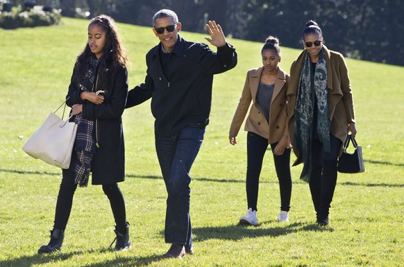 President Barack Obama waves as he walks across the South Lawn with daughter Malia, left, followed by Sasha Obama and first lady Michelle Obama, on their return to the White House, in Washington, Sund ...