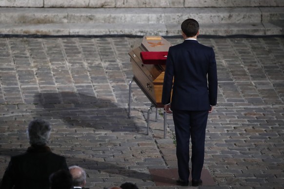 French President Emmanuel Macron pays his respects by the coffin of slain teacher Samuel Paty in the courtyard of the Sorbonne university during a national memorial event, Wednesday, Oct. 21, 2020 in  ...