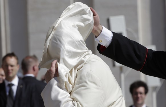 A Cardinal helps Pope Francis as a gust of wind blows his mantle, as he arrives to lead his Wednesday general audience in Saint Peter&#039;s Square at the Vatican May 14, 2014. REUTERS/Max Rossi (VATI ...