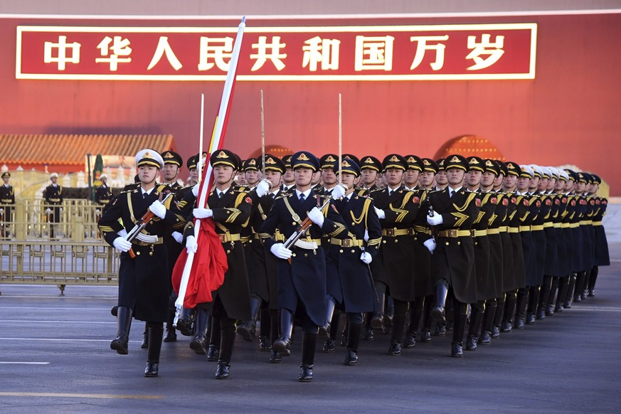 In this photo released by Xinhua News Agency, a Chinese honor guard marches with the national flag near the words &quot;Long Live the People&#039;s Republic of China&quot; on Tiananmen Gate in Beijing ...