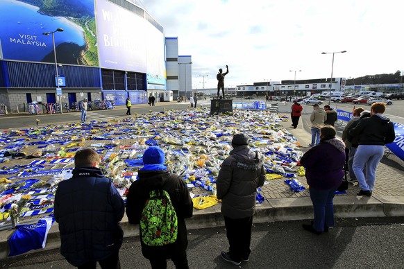 Fans look at the flowers and scarves left outside Cardiff City Stadium in tribute to Emiliano Sala, ahead of the English Premier League soccer match between Cardiff and Bournemouth at the Cardiff City ...
