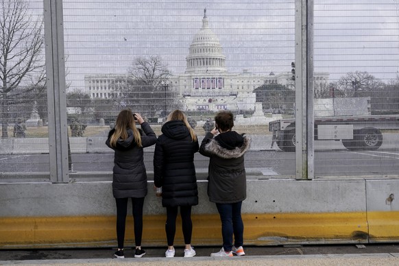 People take photos through the extensive security surrounding the U.S. Capitol in Washington, Friday, Jan. 15, 2021, ahead of the inauguration of President-elect Joe Biden and Vice President-elect Kam ...