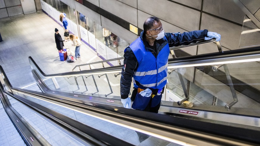 epa08334464 A worker cleans and disinfects the handles of an escalator at a metro station in Copenhagen, Denmark, 31 March 2020. The disinfection is an effort to impede the spreading of COVID-19 in De ...