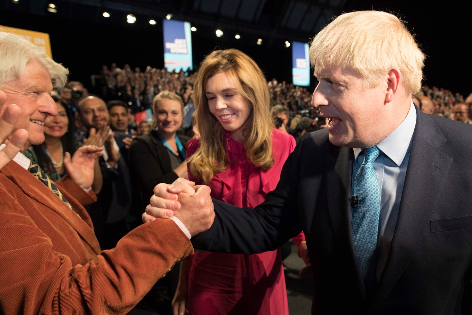 epa07889366 Prime Minister Boris Johnson leaves the stage with his partner Carrie Symonds as he is congratulated by his father Stanley Johnson after delivering his speech during the Conservative Party ...
