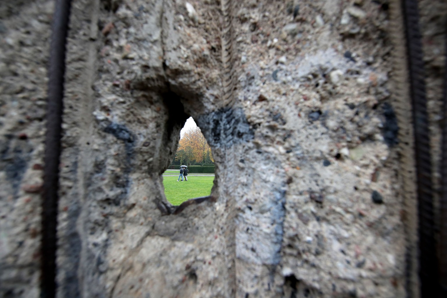 epaselect epa07983767 Visitors seen through a hole in the Berlin Wall Memorial after the celebrations of the 30th anniversary of the fall of the Berlin Wall at the Berlin Wall Memorial site along Bern ...