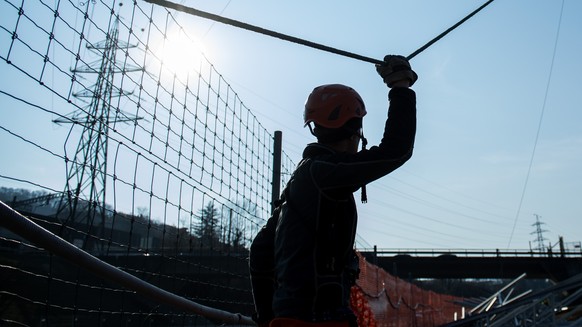 Ein Arbeiter haelt ein Seil waehrend der Konstrukion eines Hochspannungsmasts am Montag 27. Februar 2017, in Vezia im Tessin. Der Strommast des Schweizer Stromnetzes von Swissgrid wird durch die Firma ...