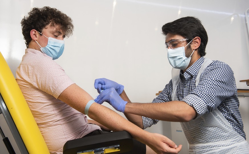 In this handout photo released by the University of Oxford a doctor takes blood samples for use in a coronavirus vaccine trial in Oxford, England on Thursday June 25, 2020. Scientists at Oxford Univer ...