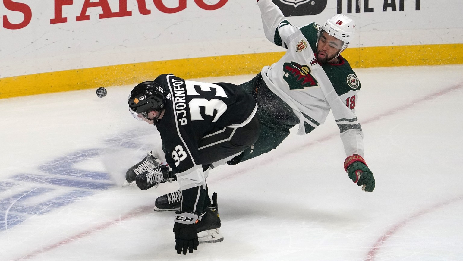 Los Angeles Kings defenseman Tobias Bjornfot, left, and Minnesota Wild left wing Jordan Greenway fall to the ice during the second period of an NHL hockey game Tuesday, Feb. 16, 2021, in Los Angeles.  ...
