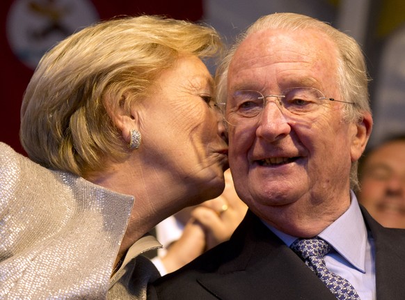 FILE - This is a Saturday, July 20, 2013 file photo of King Albert II of Belgium, right,as he is is kissed by his wife Queen Paola as they attend the national ball in the Marolles district of Brussels ...